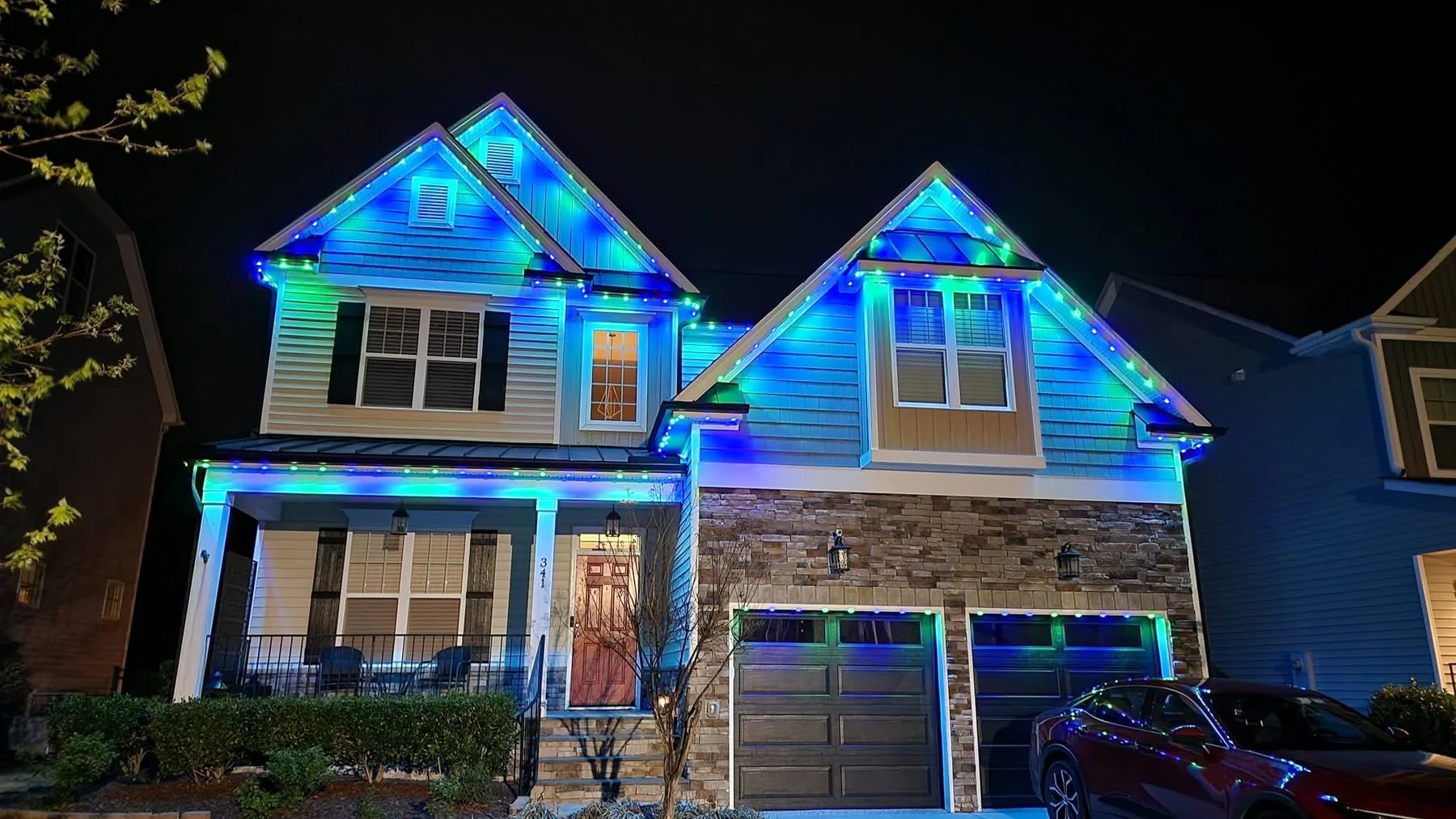 Blue and green permanent roofline lighting on a two-story home