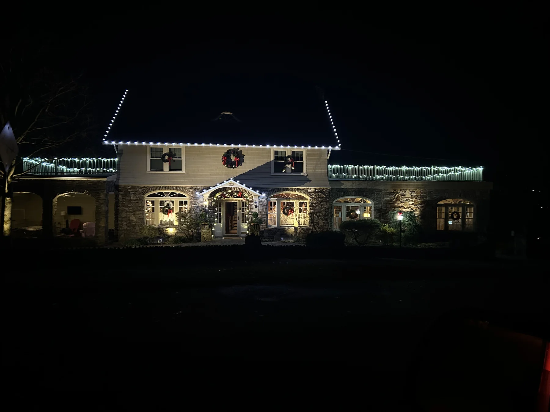 Warm white Christmas lights across a wide stone home