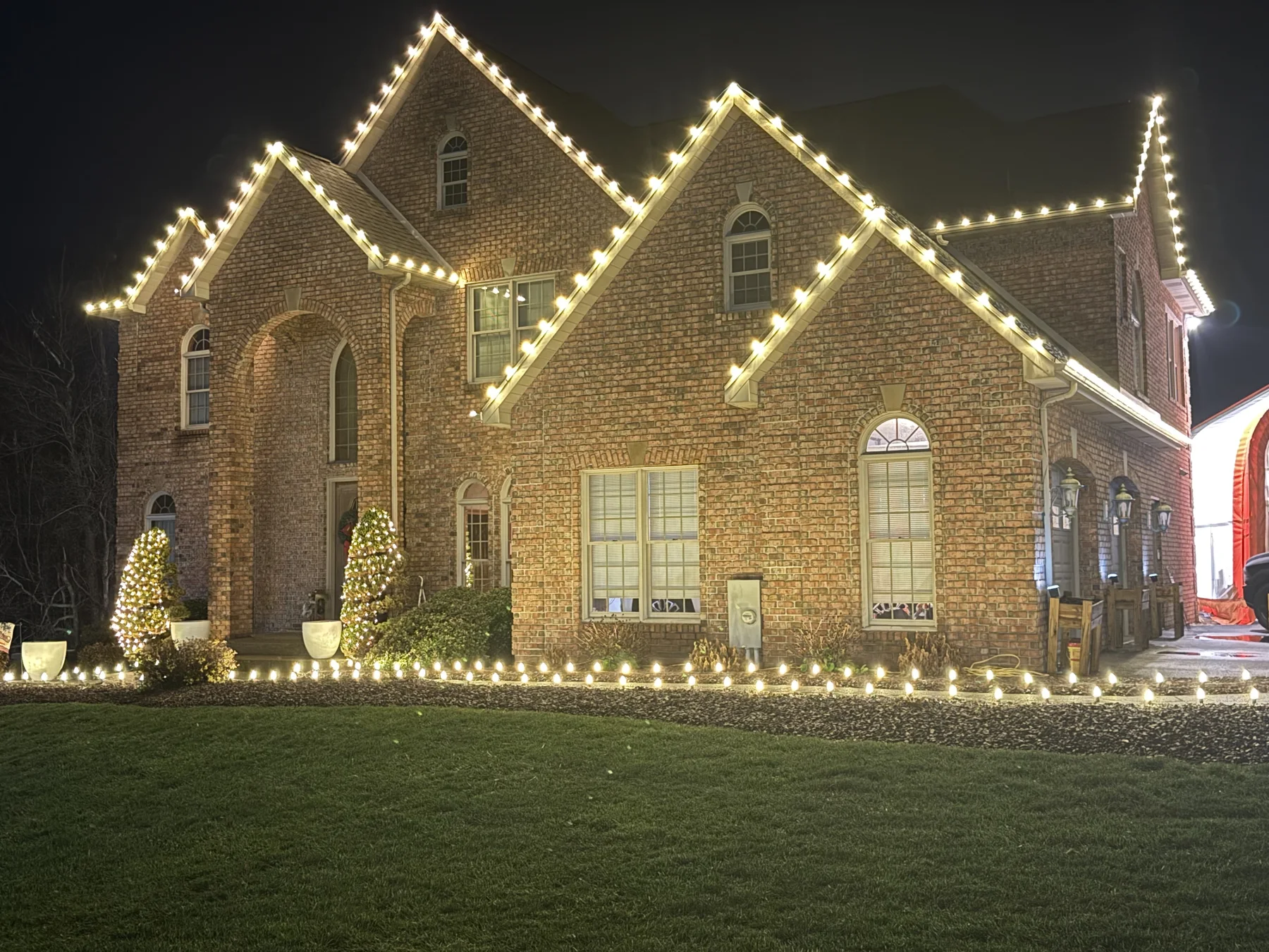 Warm white Christmas lights outlining a brick home