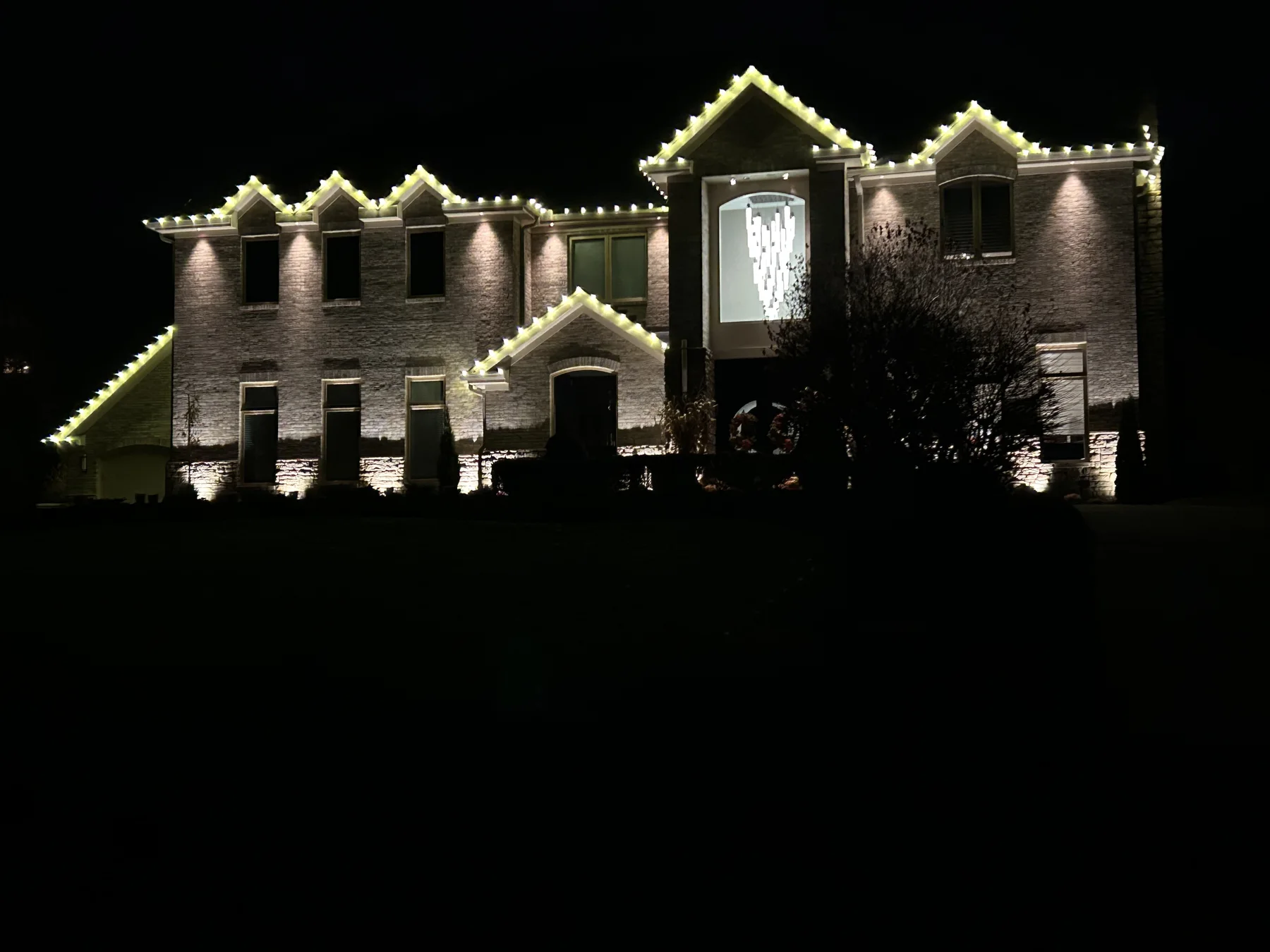 Warm white roofline and architectural Christmas lighting on a large home