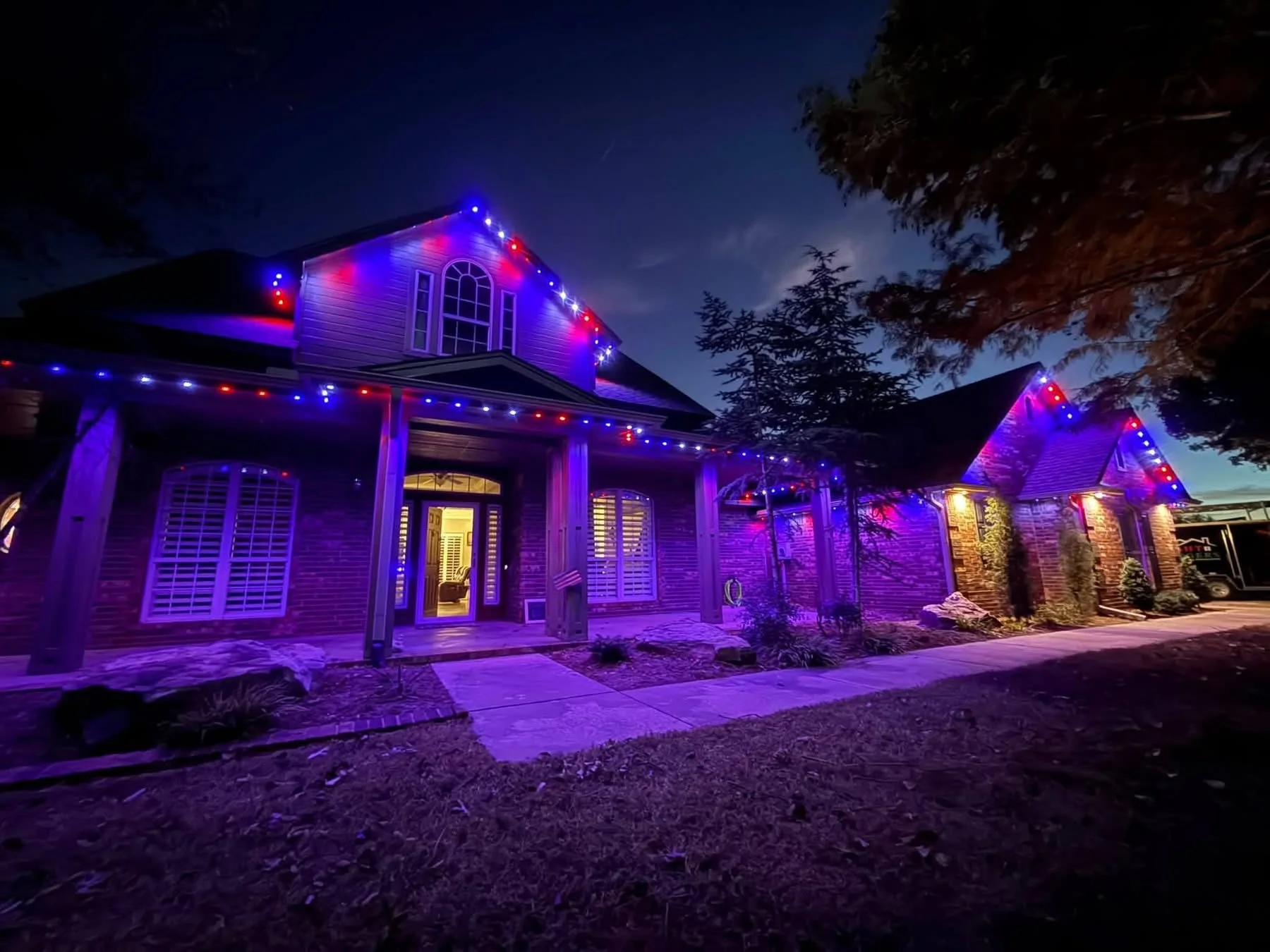 Red, white, and blue permanent roofline lighting on a large home
