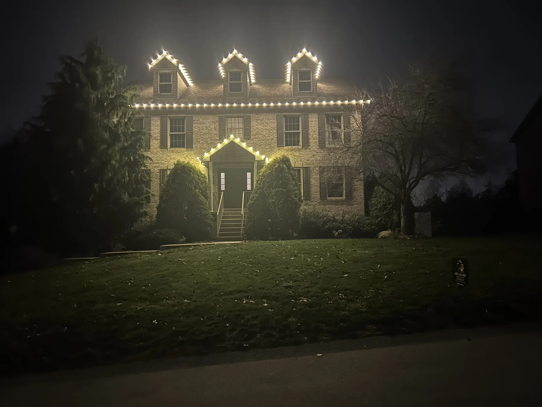 Classic warm white Christmas roofline display on a brick home