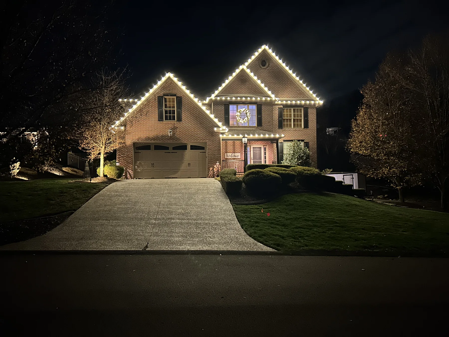 Warm white Christmas roofline lights on a home with a steep driveway