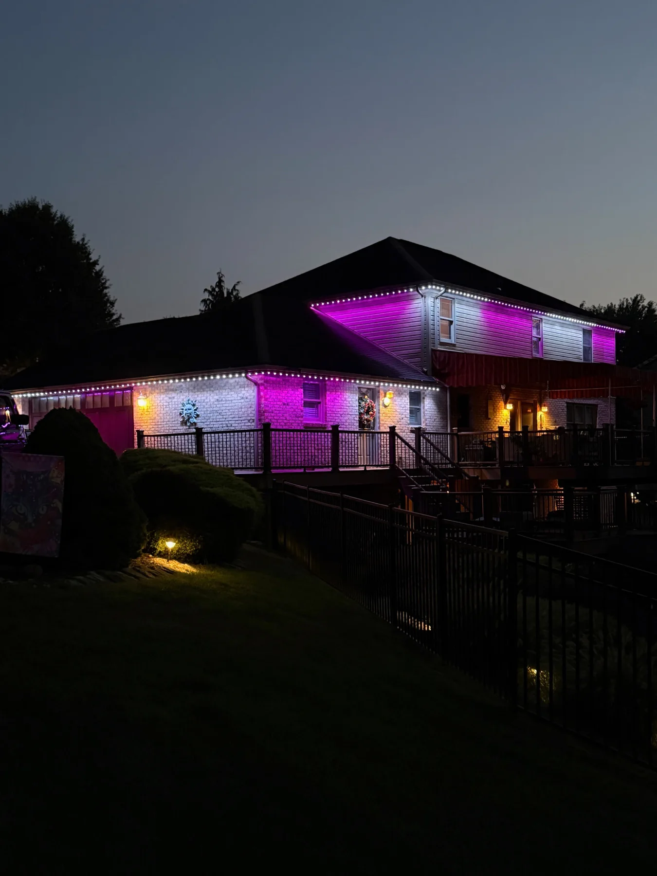 Purple and white permanent roofline lighting around a home and deck